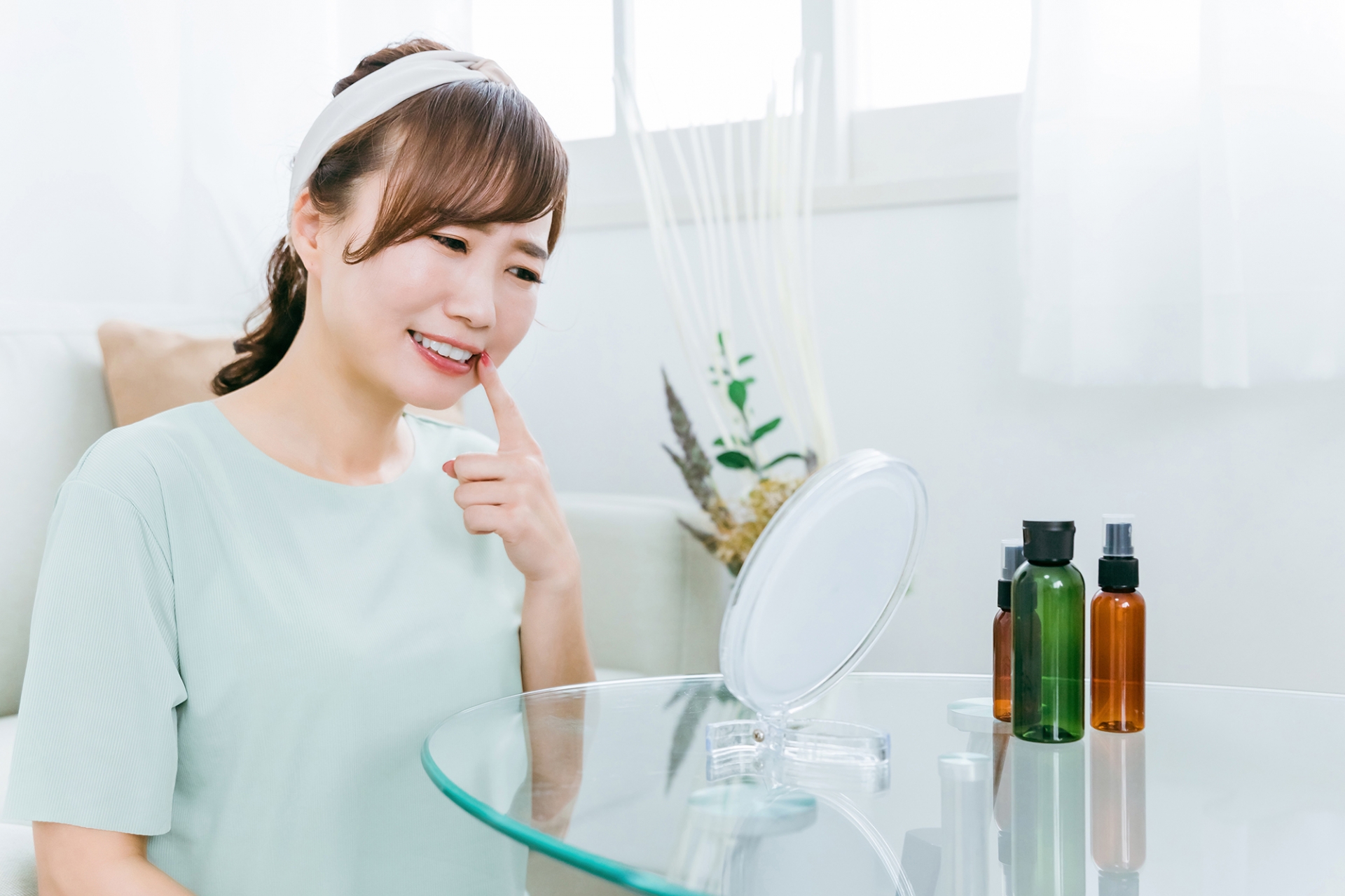鏡で欠けて黒くなった前歯を確認している女性のイメージ